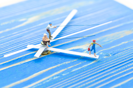 Miniature people, People use the fishing rod to take time from watch. Image use for buy the time.の写真素材