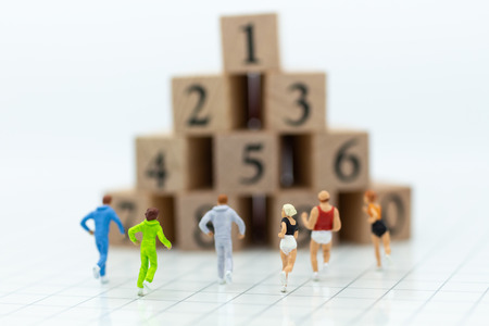 Miniature people running to stack of number wooden block . Image use for healthy , exercise concept.