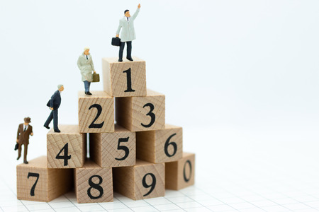 Miniature people : Businessman standing on wooden blocks with sequential numbers , win and loser....