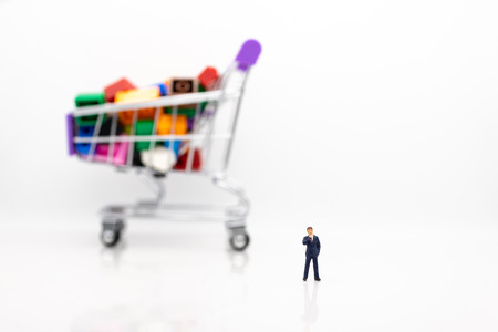 Miniature people: Businessman standing with shopping cart. Image use for shopping, marketing place...