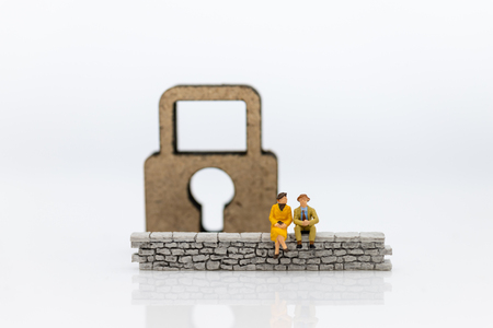 Miniature people: Businessman sitting on the wall and have master key is inside. Image use for business security center, protect conceptの写真素材