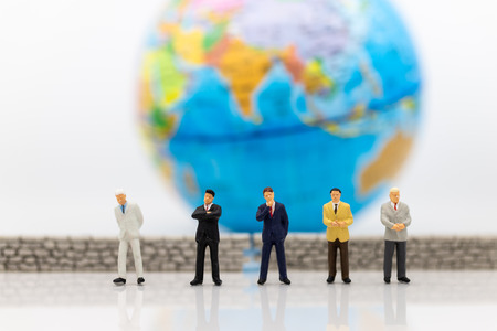 Miniature people: Businessman standing front of the wall and the world is inside. Image use for business security center, protect conceptの写真素材