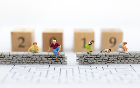 Miniature people : Businessman sitting on the wall and have wooden block 2019. Image use for business , happy new year concept.の写真素材