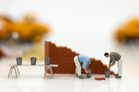 Miniature people: Construction workers building plans , have building materials, sand, brick, mortar. Use image for construction business.の写真素材