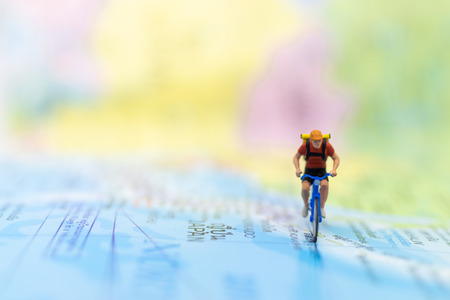 Miniature people : travel with bicycle on world map, cycling to destination on travel business...
