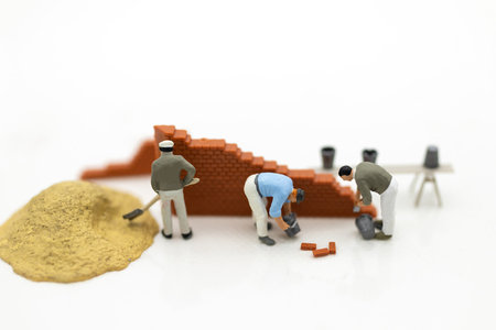 Miniature people: Construction workers building plans , have building materials, sand, brick, mortar. Use image for construction business.の写真素材