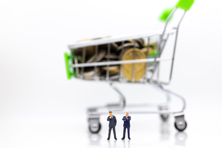 Miniature people : Businessman standing with shopping cart on stack of coin. Image use for retail business concept.の写真素材