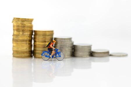 Miniature people : Travelers riding bicycle with stack of coins. Image use for background traveling and healthy, business concepts.の写真素材