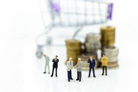 Miniature people: Businessman and stack of coins, shopping cart. Image use for online and offline shopping, marketing place world wide, business concept.の写真素材