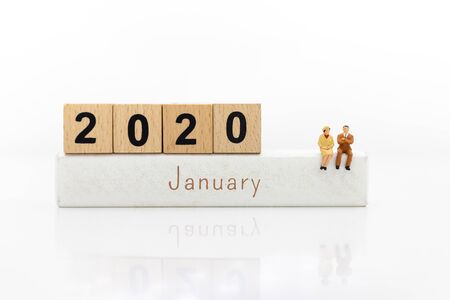 Miniature people: Businessman sitting on wooden block 2020. Image use for beginning new thing,...