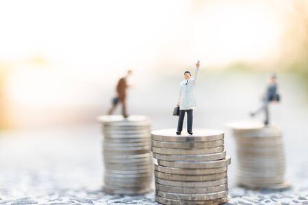 Miniature people : Businessman standing on stack of coin . Image use for business concept.