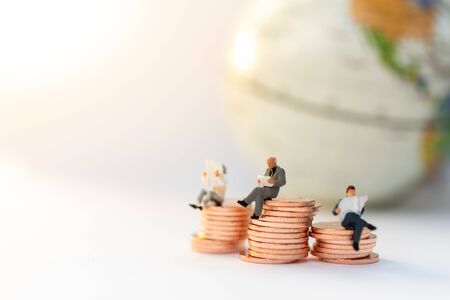 Miniature people:  Businessman sitting on the stack of coins. Image use for business concept.の写真素材