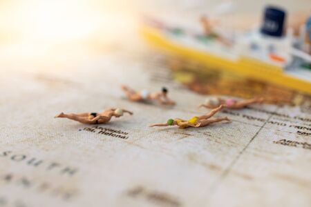 Miniature people : Young in swimsuit and friends swiming on world map. Image use for holiday, vacation concept.の写真素材