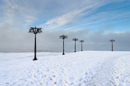 Snowy embankment along the misty river with lanterns at the foggy morning - winter landscape. Embankment of Dnepropetrovsk, Ukraine, Europeの写真素材