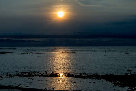 Sunset in Bali with fishermen in the distanceの写真素材