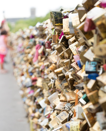 Love locks on a bridge in Paris with out of focus young girl looking at themのeditorial素材