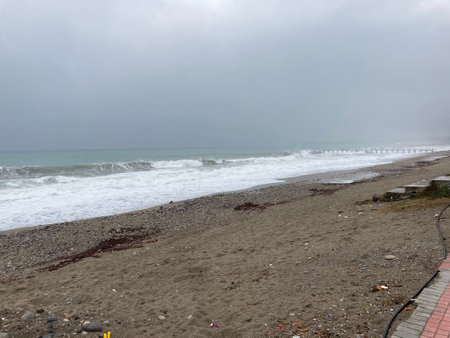 The turbulent sea storms the shore of sand mixed with pebblesの写真素材