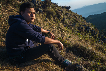 Man sitting on the mountain near the cliff looking at the viewの写真素材