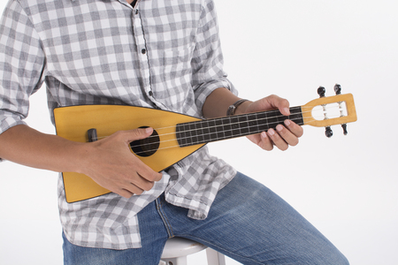 Man playing ukulele, close-up hands holding ukulele on white backgroundの写真素材