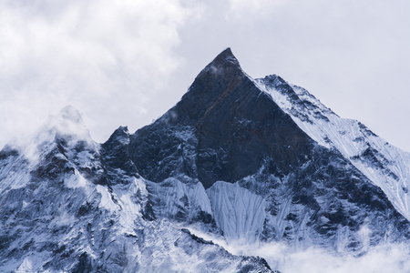 Mountain peak in Nepal. Rock mountain with snow in mistの写真素材