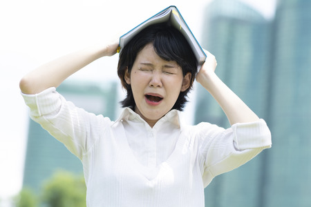 Asian woman yawning with notebook on her headの写真素材