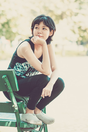 Woman relaxing in garden and sitting on benchの写真素材