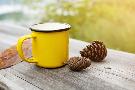 Yellow mug on wooden table with nature background in the morningの写真素材