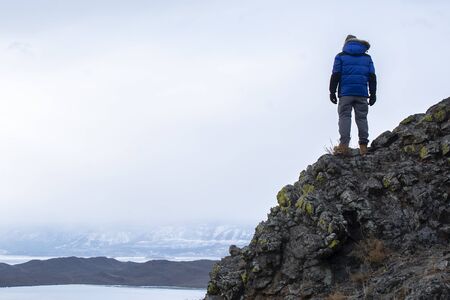 Happy man standing on cliff, man looking at landscape viewの写真素材