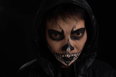 Southeast asian man with skull face makeup on black background, portrait photography