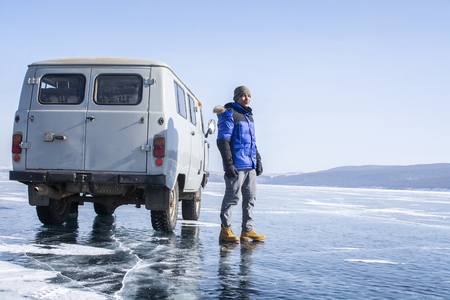 Baikal Lake, Siberia, Russia - February 22, 2019: Car is parked on frozen lake in Russia and man is standing beside it on February 22, 2019のeditorial素材