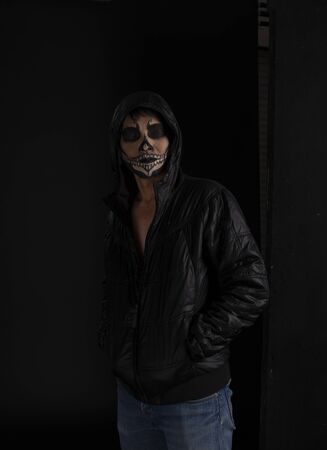 Southeast asian man with skull face makeup on black background, portrait photographyの写真素材