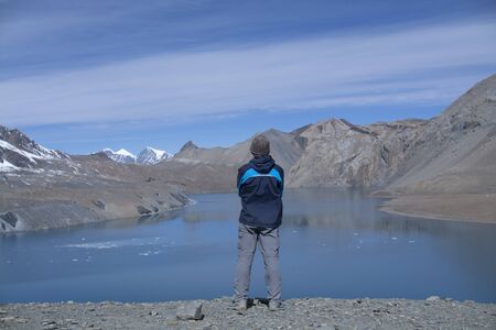 Man standing in front of lake with mountain background, Nepalの写真素材