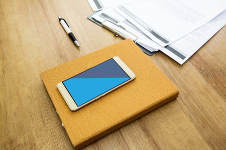 Working table with notepad, pen, document and smartphone. Wooden table background. Office background.の写真素材