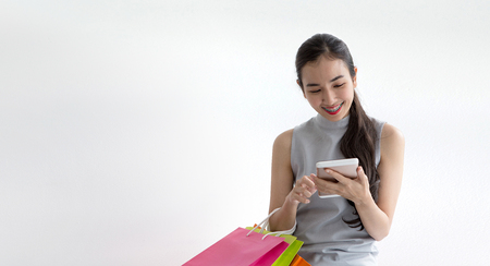Woman took a contactless payment. Lady buying online with a smart phone. Happy woman paying by smartphone or tablet. Girl on white background.の写真素材