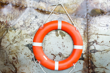 SOS Concept. Rubber ring hang on the Steel wall. Orange life saving rubber. Red lifebelt on wall...
