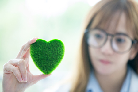 Science whit green spirit mind. Green heart in her hand on lab a background. Beautiful smiling female doctor or Scientist holding organic heart-shaped. asian lab. science room.の写真素材