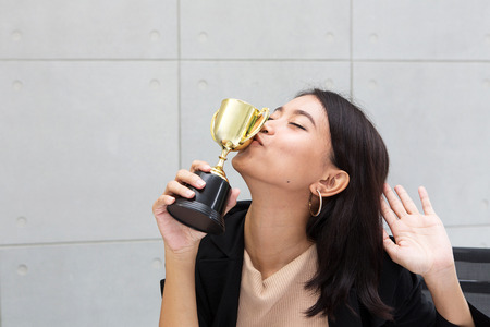 Office worker kissing trophy. A business woman or Employees is holding a trophy and kissing it....