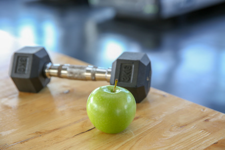 Healthy lifestyle sport. Dumbells, and healthy food on wooden.  green apple in the gym or sport club. Healthy lifestyle sport equipment fitnessの写真素材
