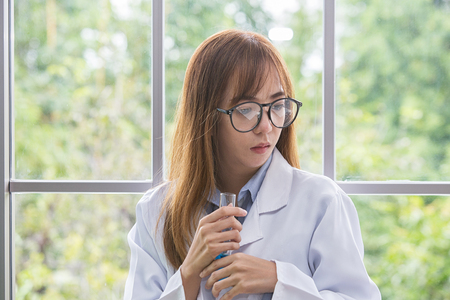 Science whit blue spirit mind. Scientific substance blue in on her hand at lab a background. Beautiful Female doctor or Scientist holding Scientific substance organic. asian people.の写真素材