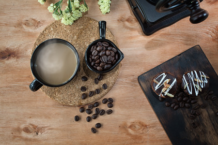 Coffee grinder, Coffee bean, Coffee and sweets. Coffee cup and sweets on wooden table.