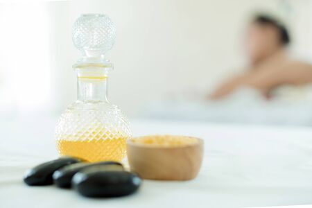 Natural cosmetics and concept. Close up of salt with massage oil and bath towel on Spa bed. Bottle of massage oil, hot stone spa and salt With the backdrop of a woman massage in a beauty spa bed.の写真素材