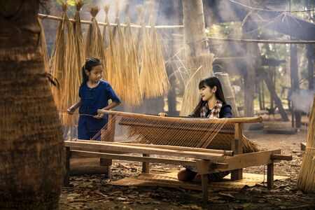 Asian girl is weaving the mat. Girl weaving mats in the countryside. Nong Khai, Thailand.の写真素材