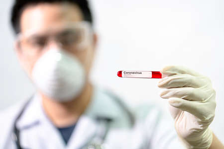 Doctor Hand holding test tube. Test tube with blood sample positive with coronavirus. Asian doctors...