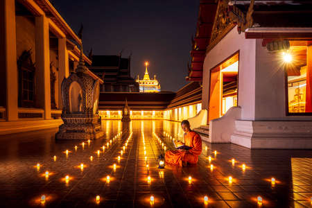 Night Urban City Skyline of Landmark Bangkok. Wat Saket. Night scene of Phu Khao Thong (Golden Mountain) and monk reading a book.のeditorial素材