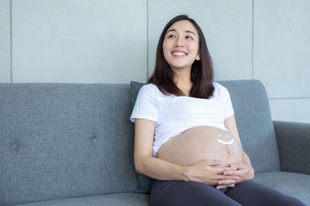 pregnant and write icon happy. Pregnant woman with cream write face happy on the belly.の写真素材