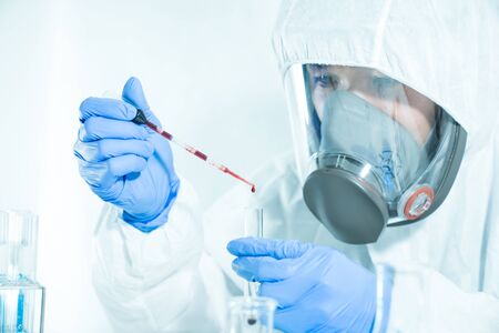 Scientists are dropping blood into a glass tube in a science lab to search for a virus....