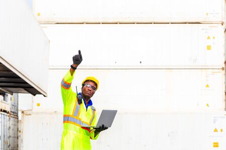 Foreman using laptop computer in the port of loading goods. Foreman showing thumbs up on Forklifts...