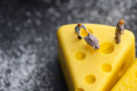 A tiny worker model is working on a cheesecake. model the worker, miniature company employee , employer figure.の写真素材