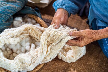 Craftsmen of Thai indigo cotton. An elderly woman is examining the thread made of cotton. Local Master are the original Indigo Cotton Weaving in the community of Sakon Nakhon province.の写真素材