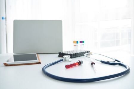 Tablet, laptops, medical stethoscope and blood tubes on table. Selective focus.の写真素材